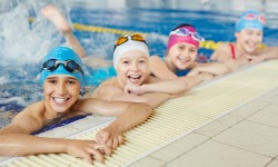 Kinder mit Badehauben und Schwimmbrillen im Schwimmbad