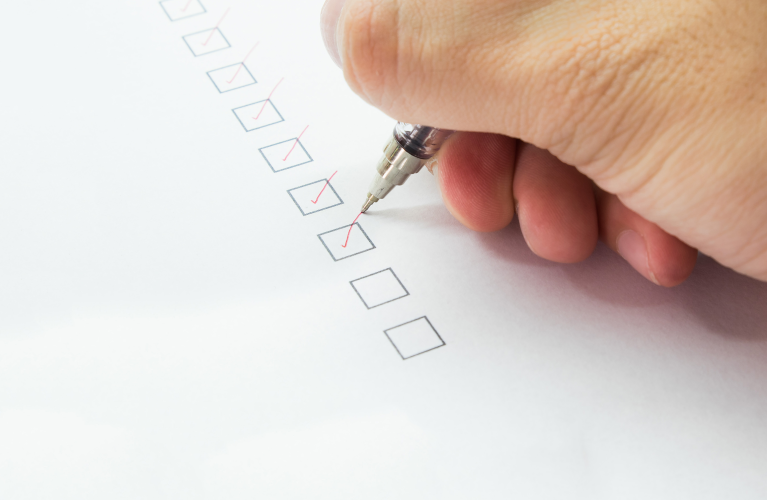 Hand markiert erledigte Punkte auf einer Checkliste
