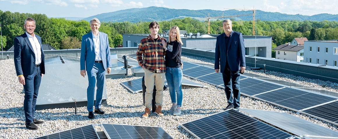 Vier Männer und eine Frau stehen vor einer Photovoltaikanlage.