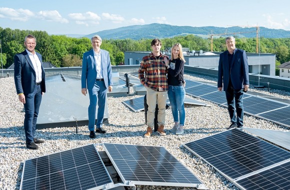 Vier Männer und eine Frau stehen vor einer Photovoltaikanlage.