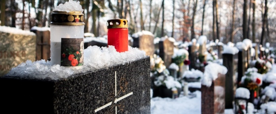 Grabstein im Freien mit Kerzen und von Schnee bedeckt