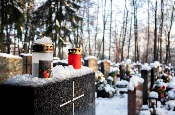 Grabstein im Freien mit Kerzen und von Schnee bedeckt
