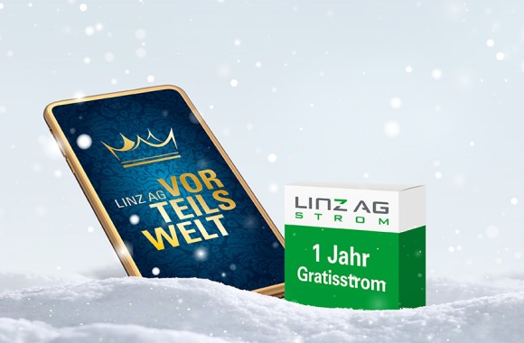 Smartphone mit Vorteilswelt-App am Display steckt im Schnee, daneben eine Schachtel mit der Aufschrift 1 Jahr Gratisstrom und Weihnachtsmütze