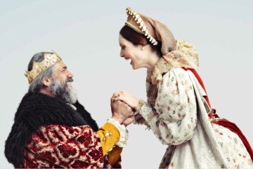 König kniet vor der Königin und macht ihr einen Antrag. Sie lachen sich an.
