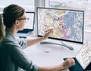 Frau zeigt auf Bildschirm wo eine Stadtkarte zu sehen ist